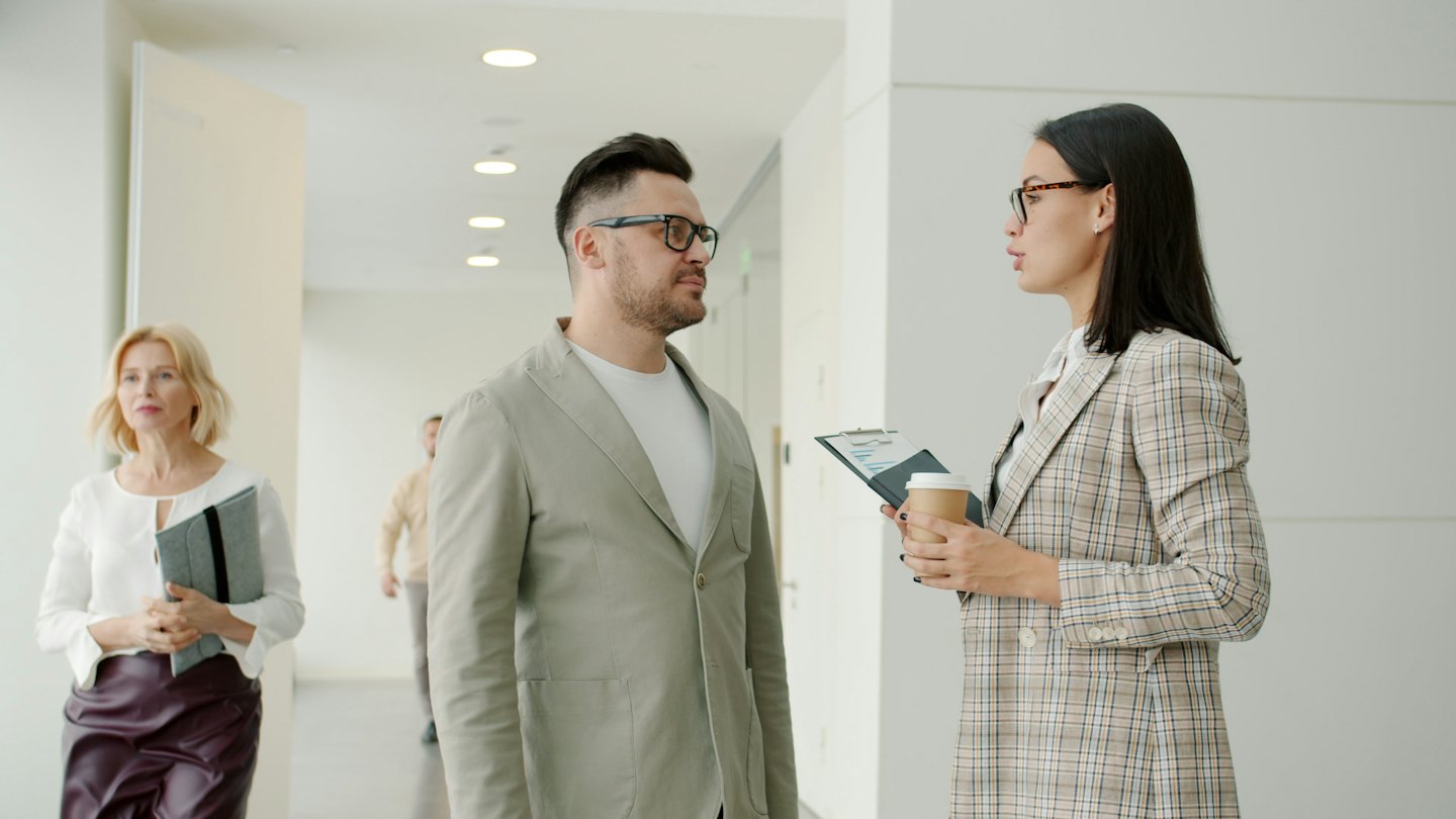 Due professionisti d'affari che parlano in un moderno corridoio d'ufficio.
